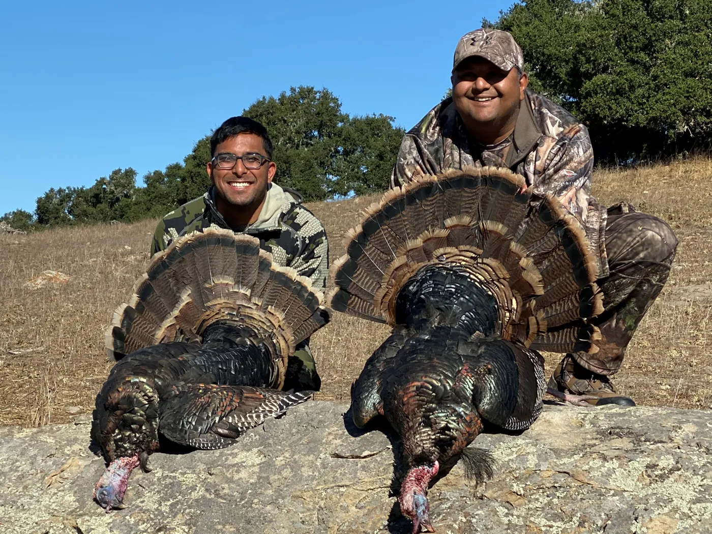 Nikhil and Shiven kneeling with two wild turkeys